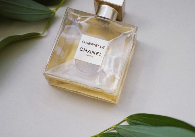 A squared glass bottle full of golden perfume labeled Gabrielle by Chanel